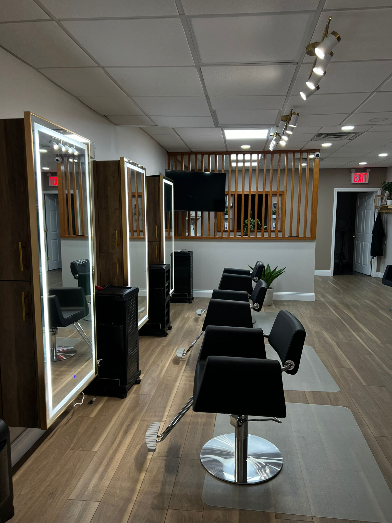Illuminated styling mirrors and black chairs with wood accents