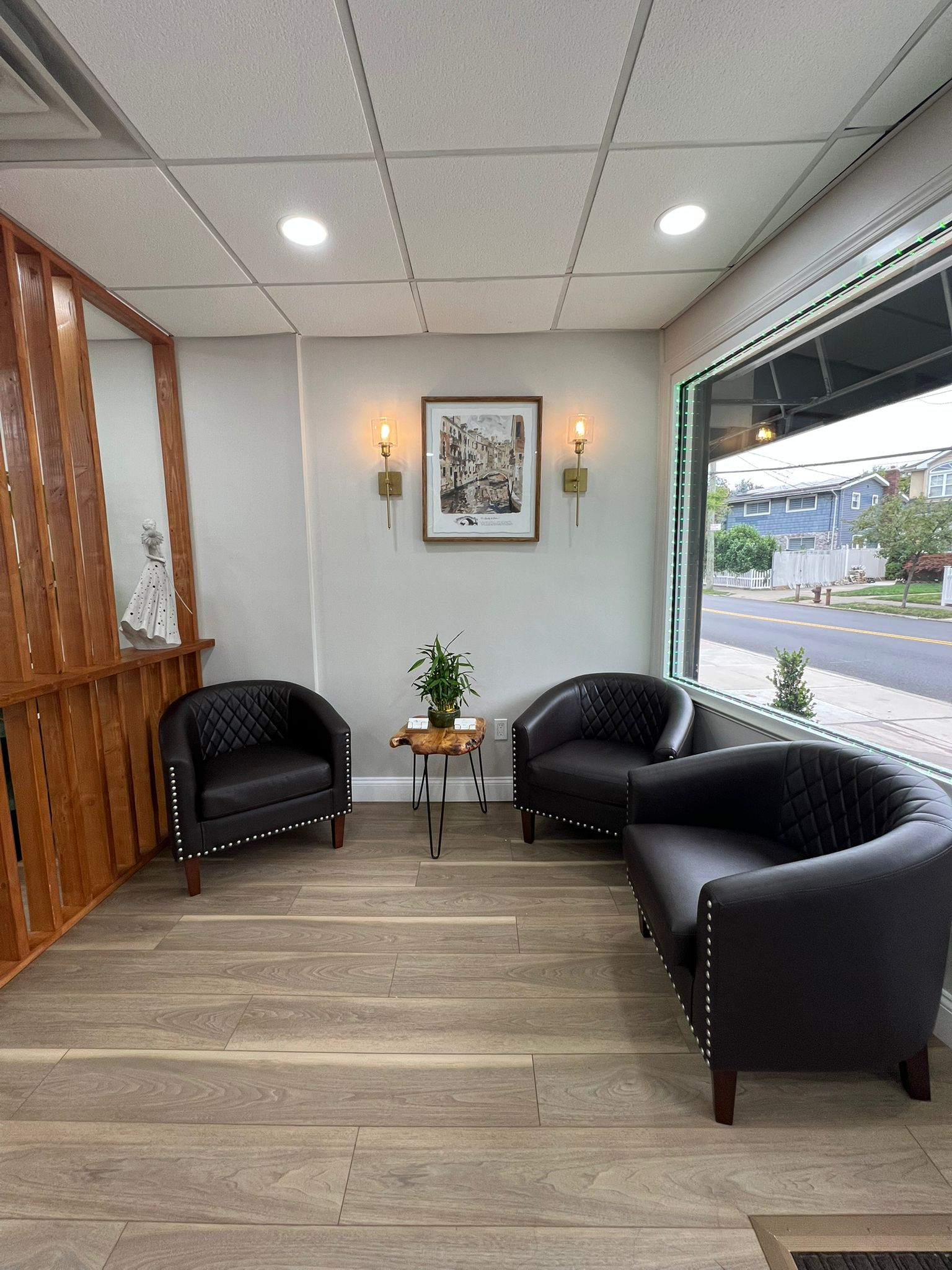 Salon waiting area with three black armchairs and warm sconces